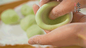 將均分的艾草面團搓成圓，挖一個窩，放入餡心，再搓成圓。