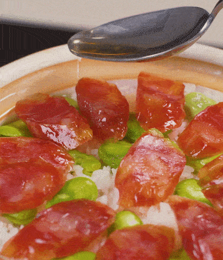 大米出現(xiàn)小孔時開蓋放香腸，往鍋邊淋入少許油，再燜煮8~10分鐘左右。