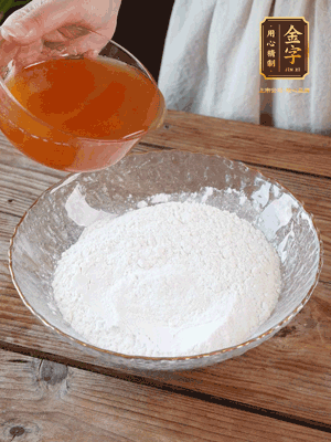 轉(zhuǎn)化糖漿、枧水、花生油攪拌均勻，加入面粉混合，醒發(fā)2小時(shí)。捏成23g一個(gè)的小球